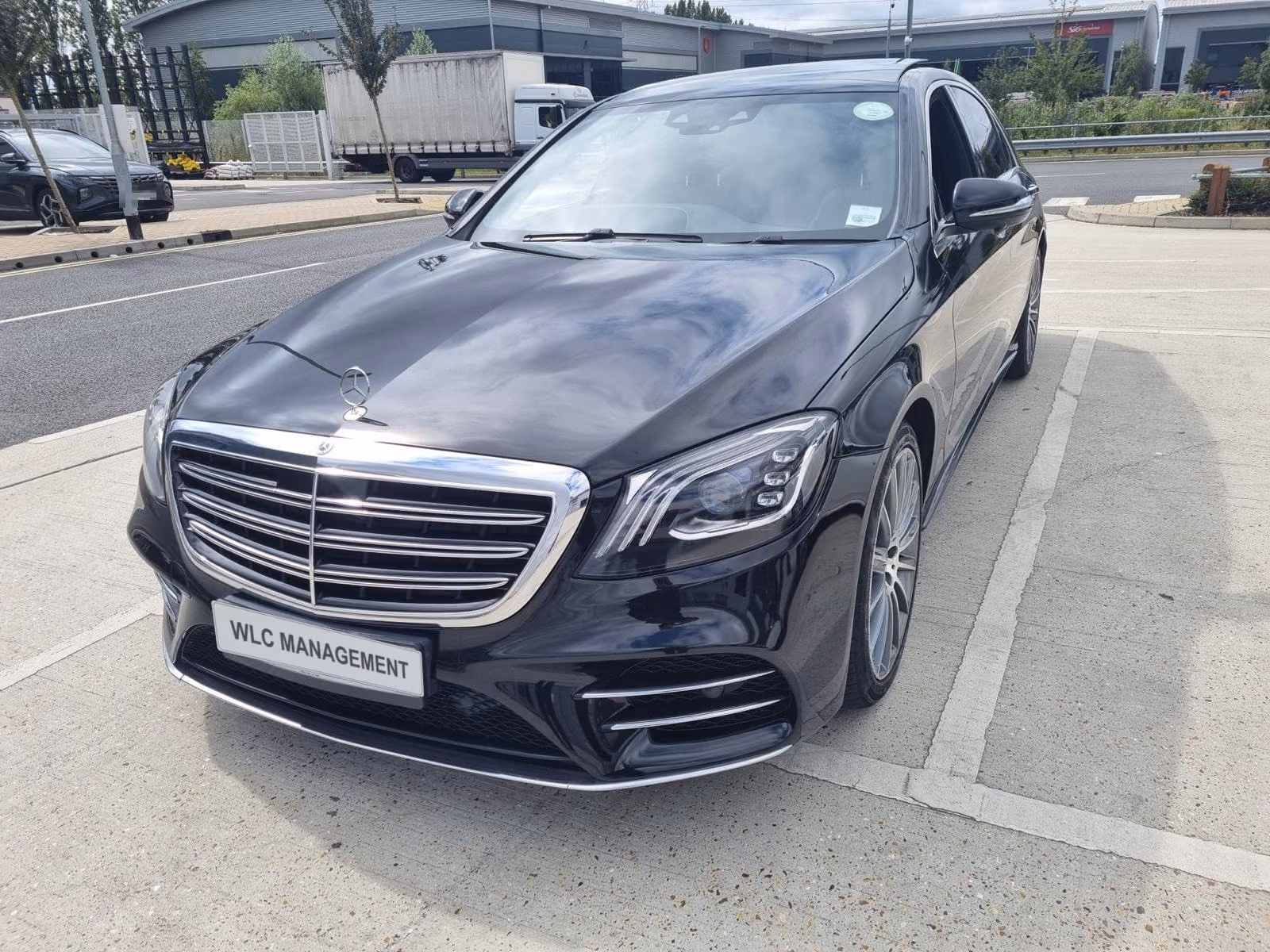Black Mercedes-Benz S-Class parked outside, front three-quarter view, deep gloss on the bonnet