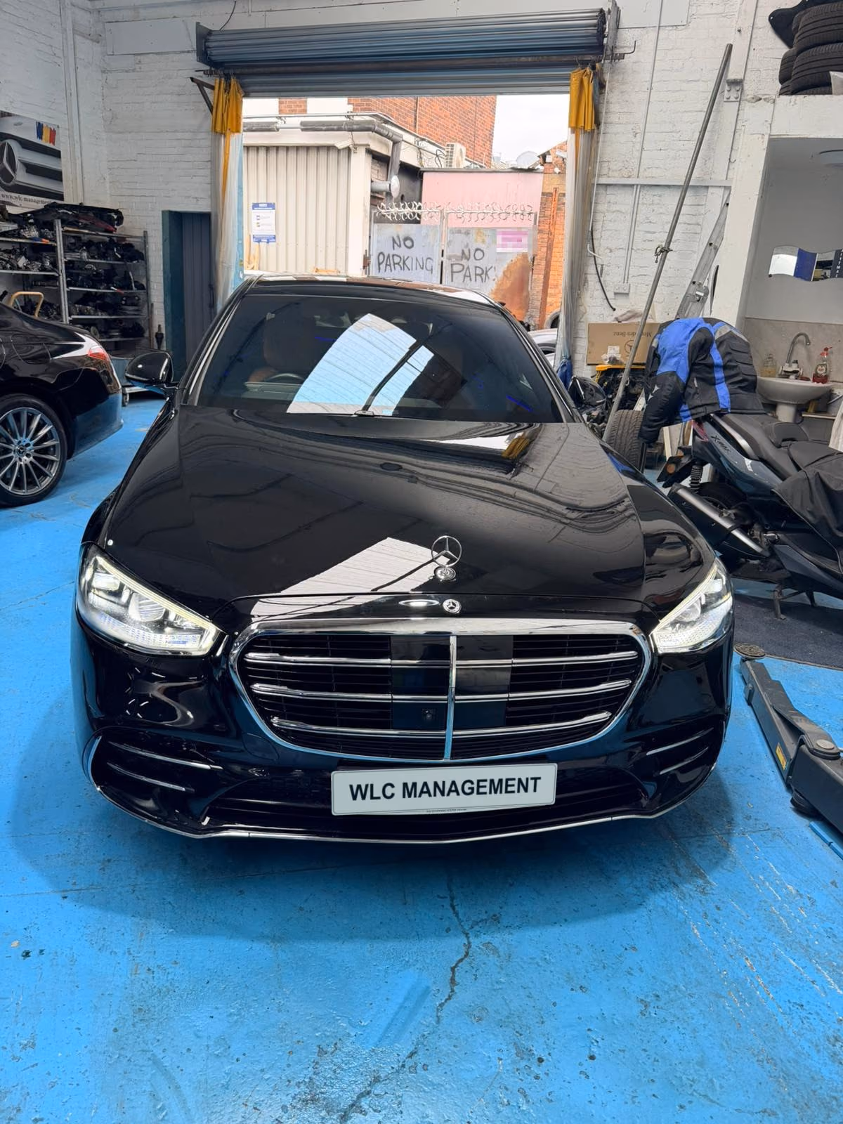 Black Mercedes-Benz S-Class on the blue workshop floor, front view